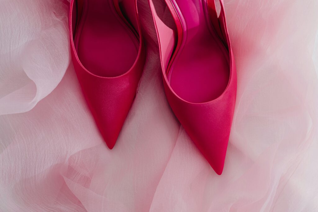 hot pink high heel shoes on top of a light frilly pink lace fabric.